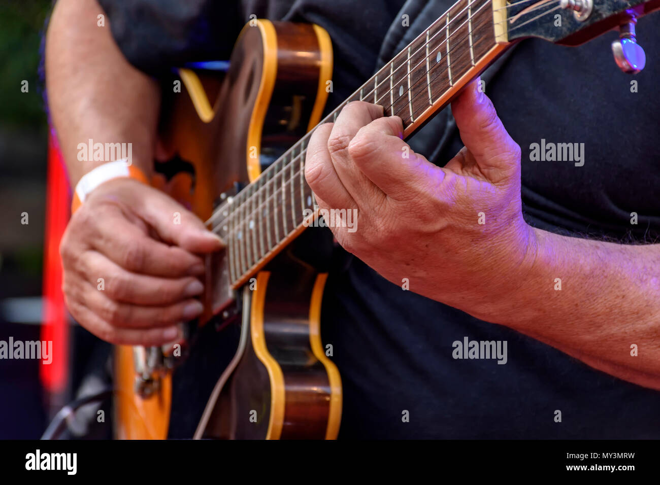 Dettaglio del chitarrista con le mani in mano e il suo nero chitarra elettrica a un esterno di presentazione di jazz Foto Stock