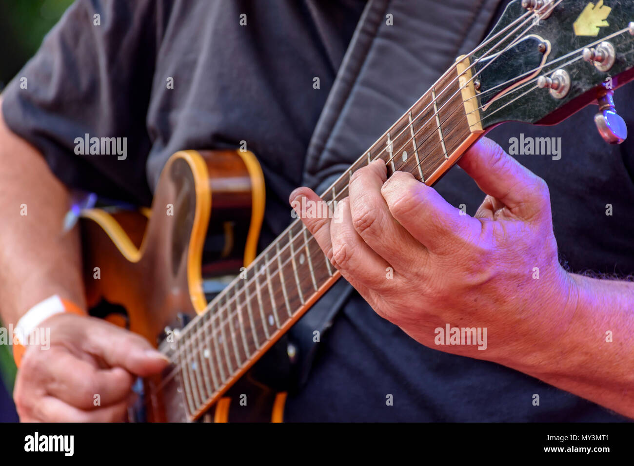 Dettaglio del chitarrista con le mani in mano e il suo nero chitarra elettrica a un esterno di presentazione di jazz Foto Stock