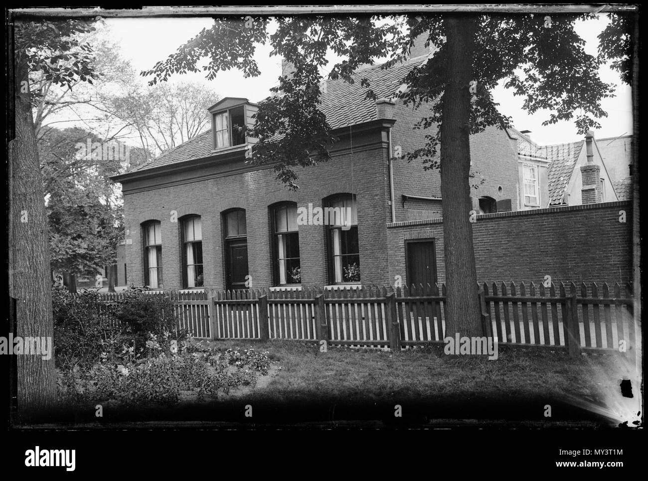 Woning. Baksteen woning met veel hoge ramen, leisteen dak en dakkapel, gezien vanuit tegenovergelegen tuin met hoge bomen Den Helder 1930 Catalogusnummer: RAA003012608 Collectie Regionaal Archief Alkmaar Foto Stock