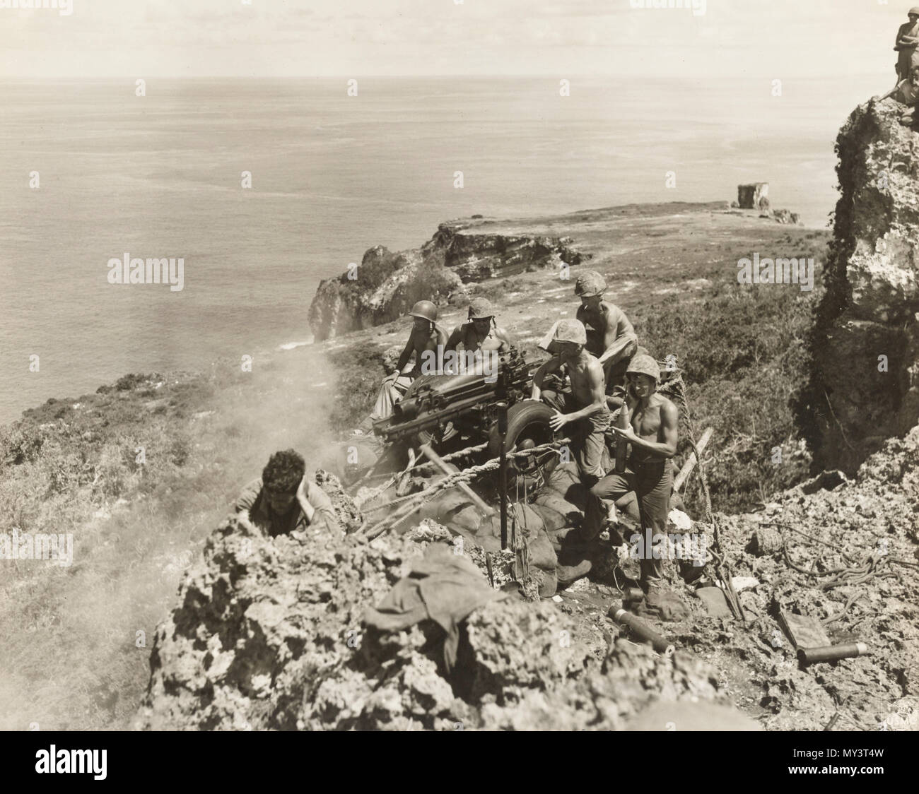 8 25 1944 marines manning un campo obice blast un nido Giapponesi in una grotta dal bordo di una scogliera a strapiombo su Tinian Foto Stock