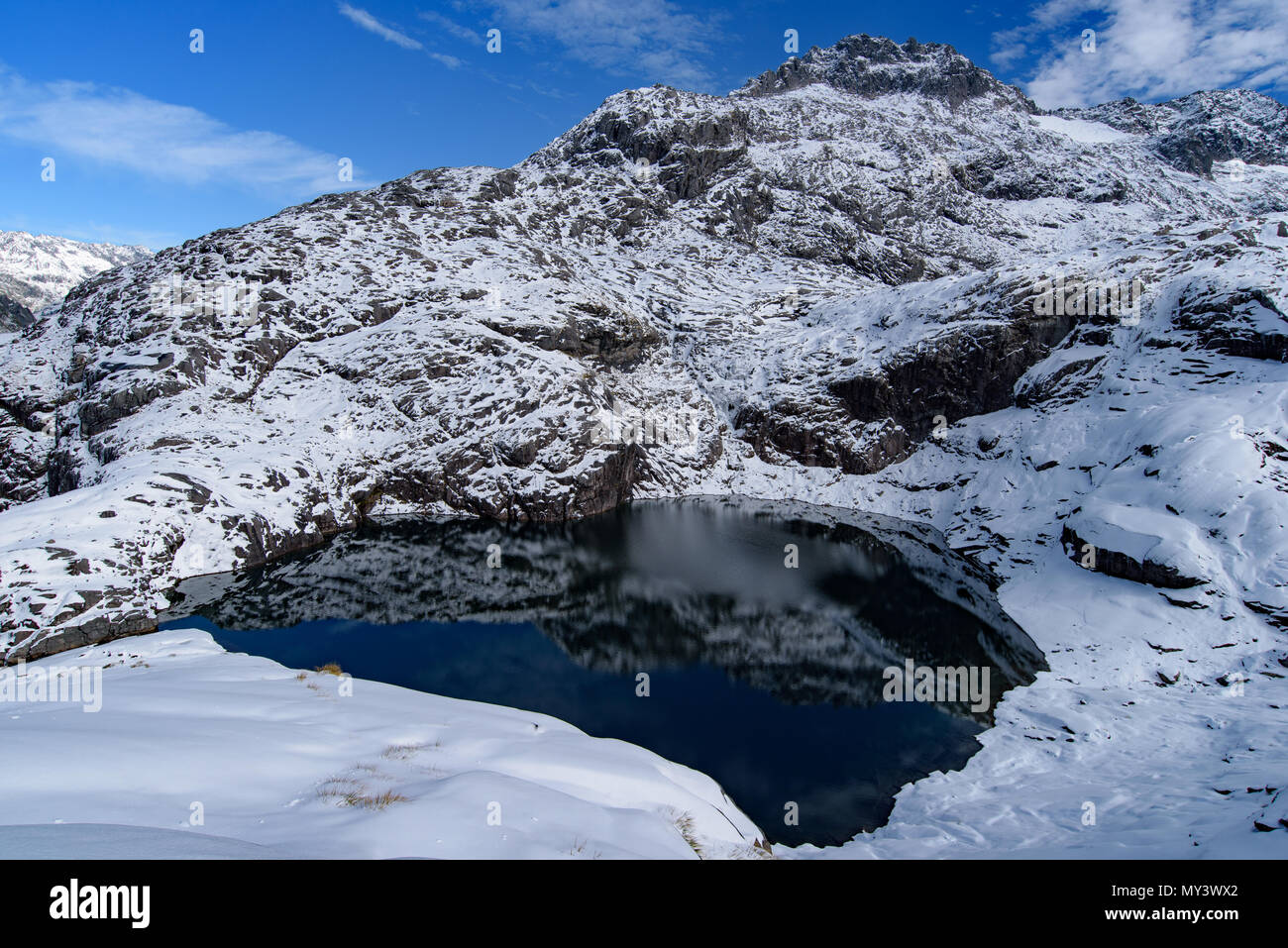 Un lago nelle montagne innevate nel Parco Nazionale di Fiordland, Nuova Zelanda Foto Stock