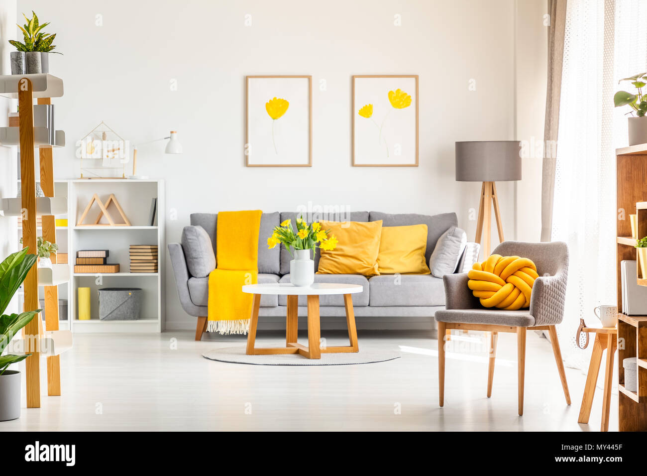 Nodo giallo cuscino sulla poltrona di colore grigio nella vita moderna sala interna con poster sopra il lettino. Foto reale Foto Stock