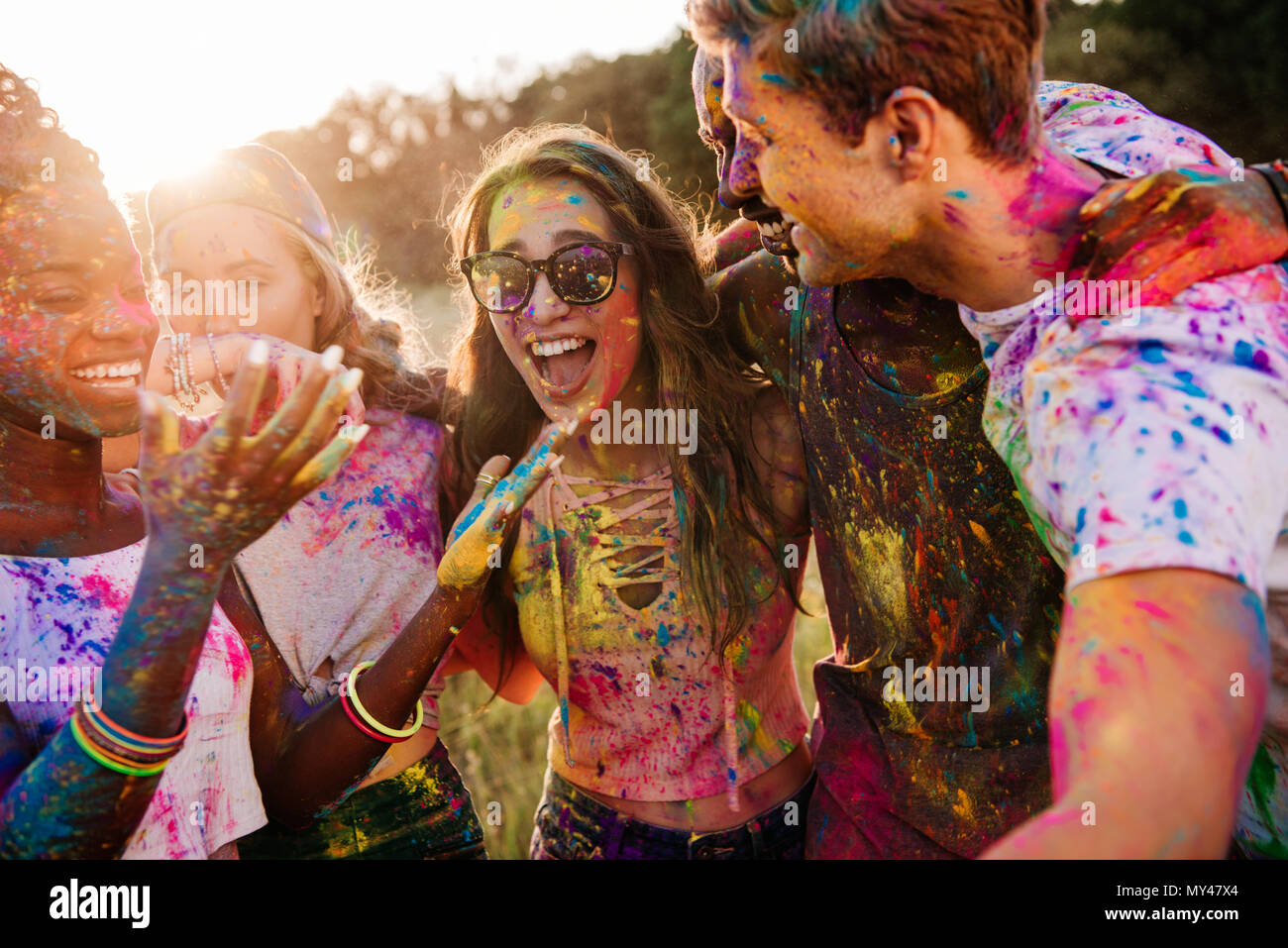 Allegro giovani amici multietnico con vernice colorata su abiti e corpi di divertimento insieme a Holi festival Foto Stock