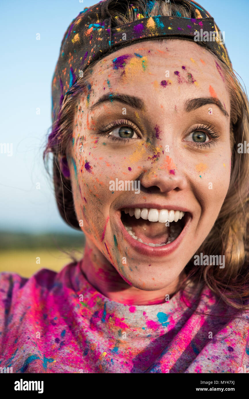 Close-up ritratto di bella donna eccitate con vernice colorata sul viso e vestiti che guarda lontano a Holi festival Foto Stock