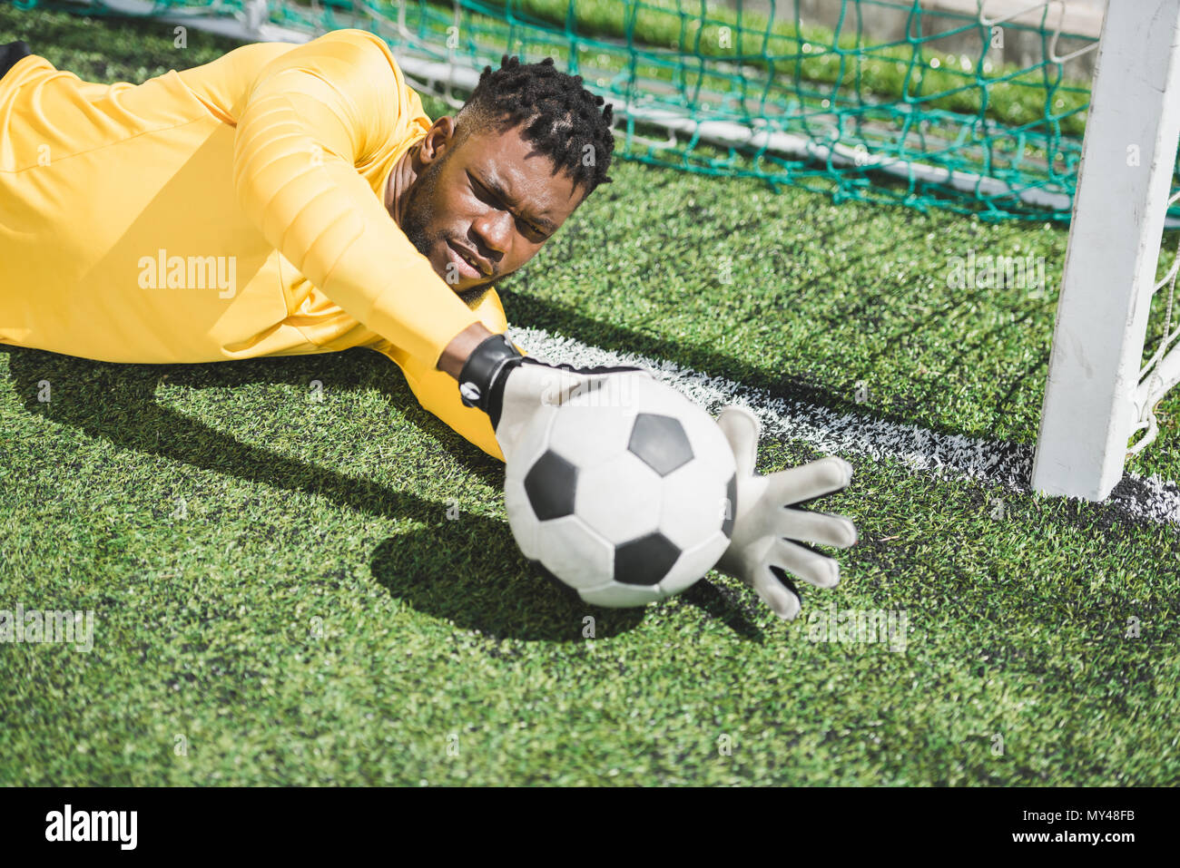 Ritratto di African American portiere cattura la sfera durante la partita di calcio Foto Stock