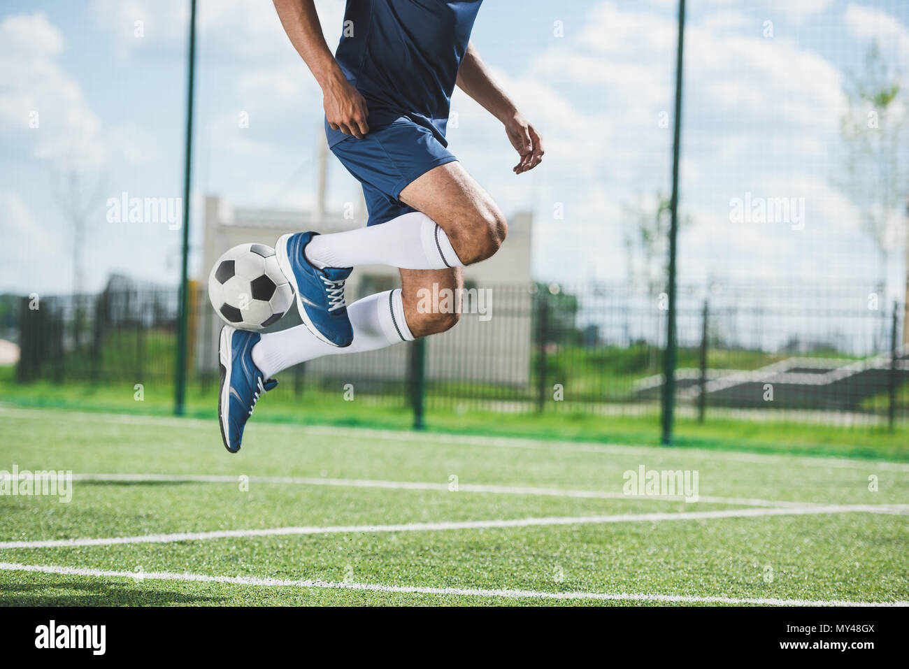 Ritagliato tiro del giocatore di calcio jumping con la palla sul campo di calcio Foto Stock Ritagliato tiro del giocatore di calcio jumping con la palla sul campo di calcio Foto Stock