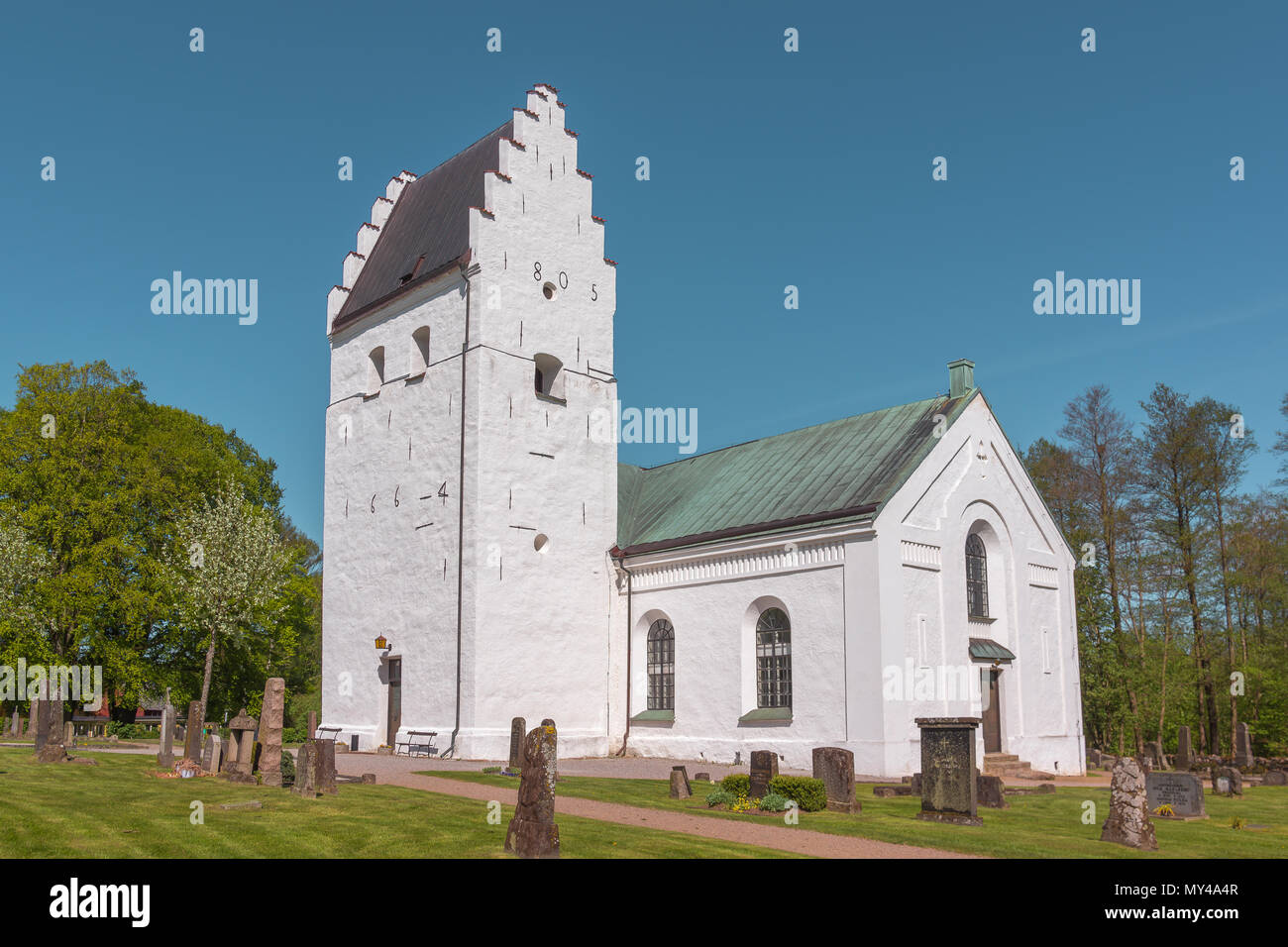 Un bianco scandinavo chiesa medievale con timpani a gradini e lapidi nel prato verde, Finja, Svezia, 9 maggio 2018 Foto Stock