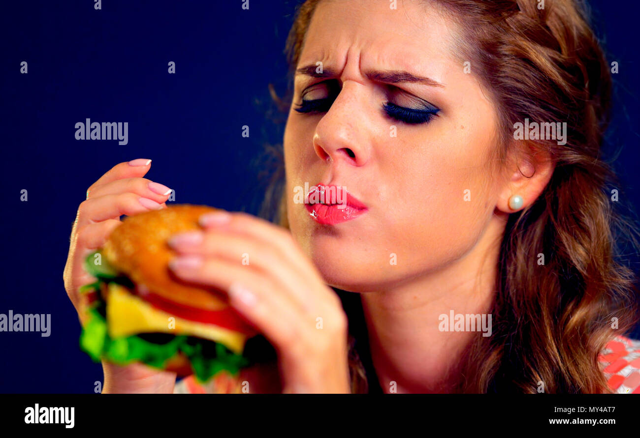 Donna di mangiare fast food. Ragazza gustare deliziosi hamburger. Foto Stock