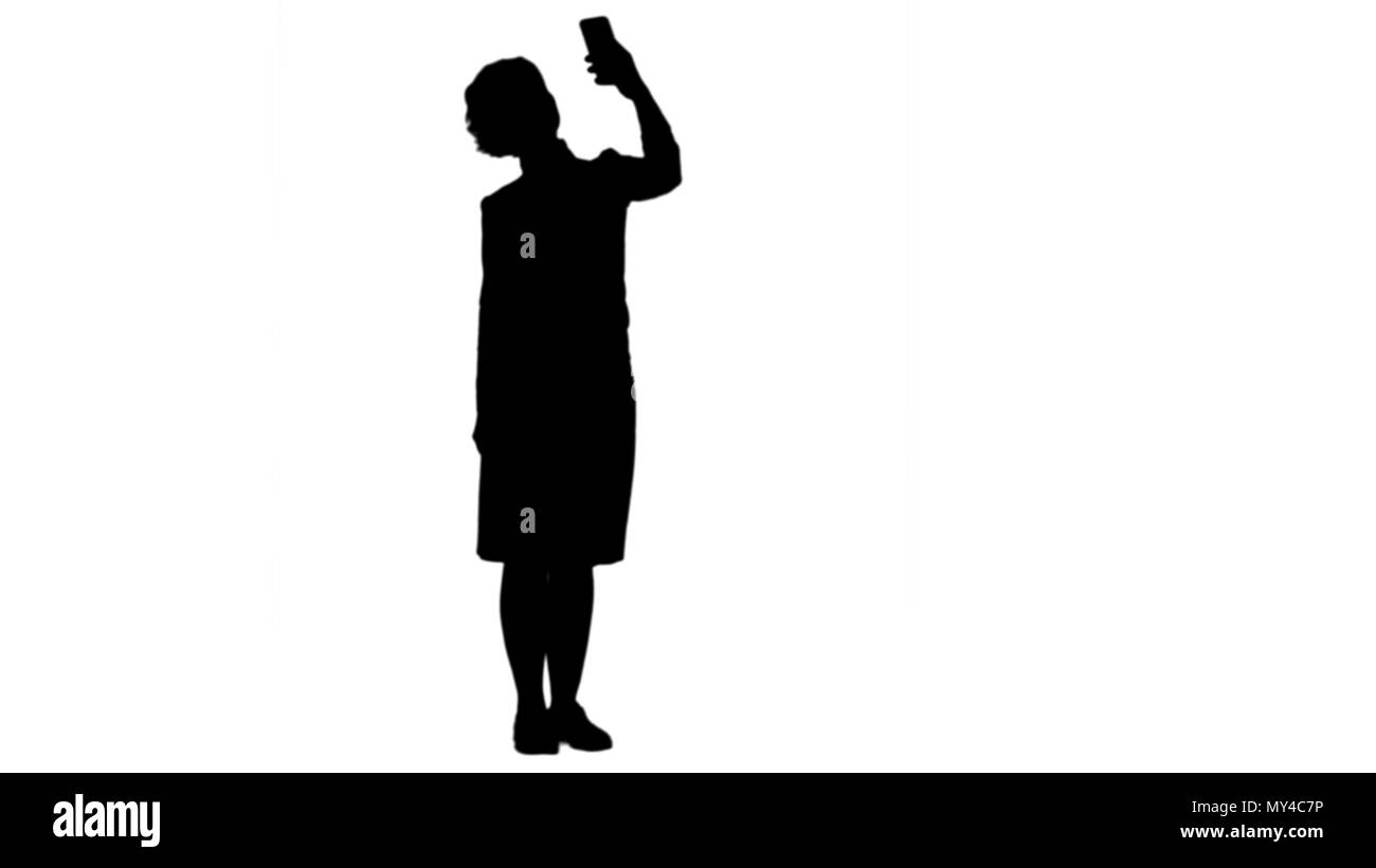 Silhouette sorridente carino donna fare selfie foto sullo smartphone via matte Foto Stock