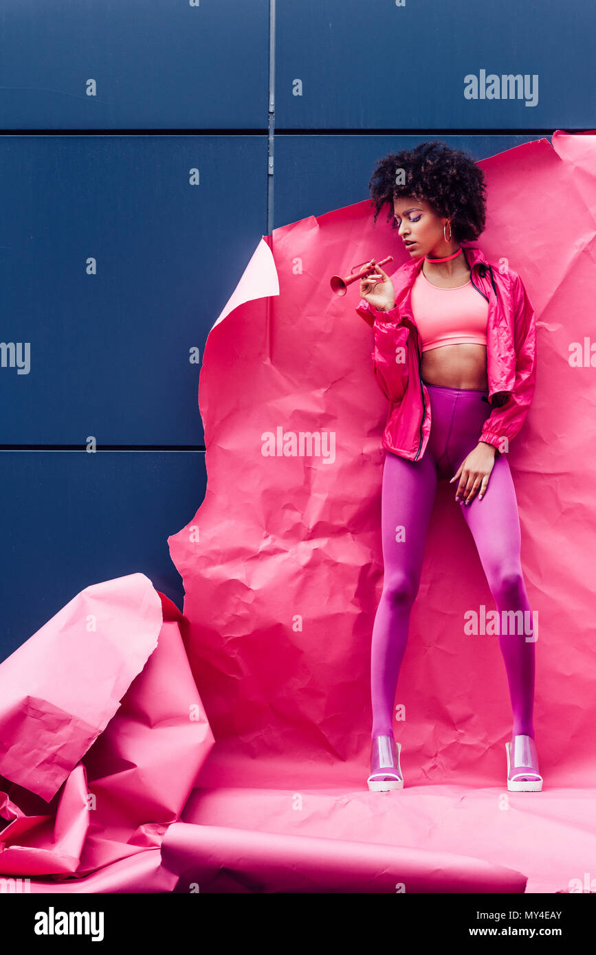 Moda africana modello americano con tromba in posa di 80s vestiti in stile con la carta rosa Foto Stock