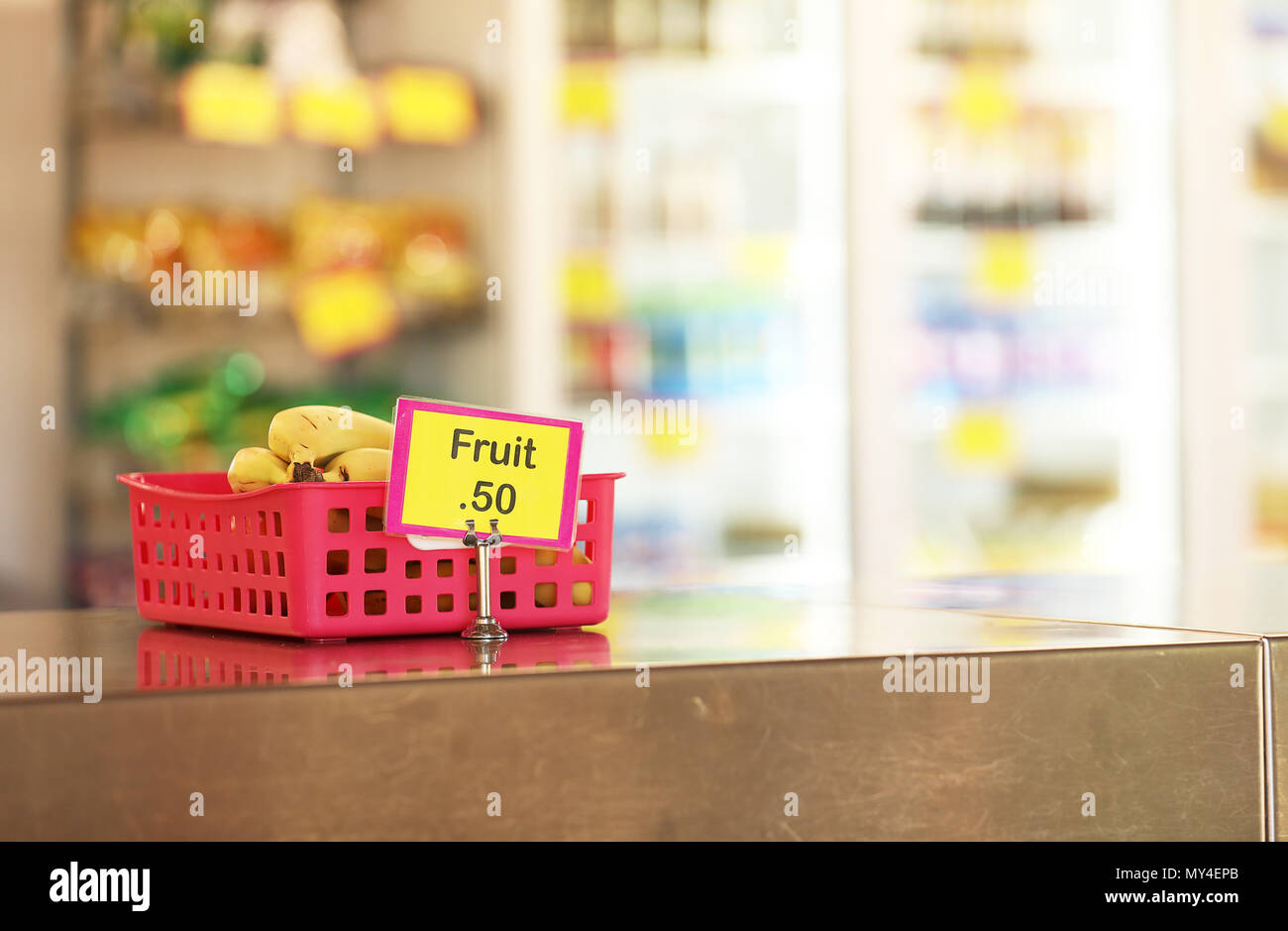 Mensa scolastica negozio di dolciumi caff vendita frutta sani opzioni di cibo per gli studenti. banane in un rosso sul vassoio in acciaio inox panca in primo piano Foto Stock