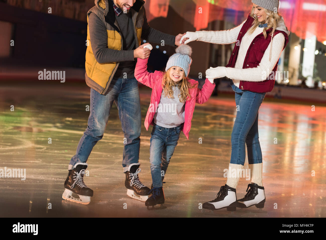 Ritagliato colpo di genitori felici di insegnamento poco adorabile figlia il pattinaggio su ghiaccio Foto Stock