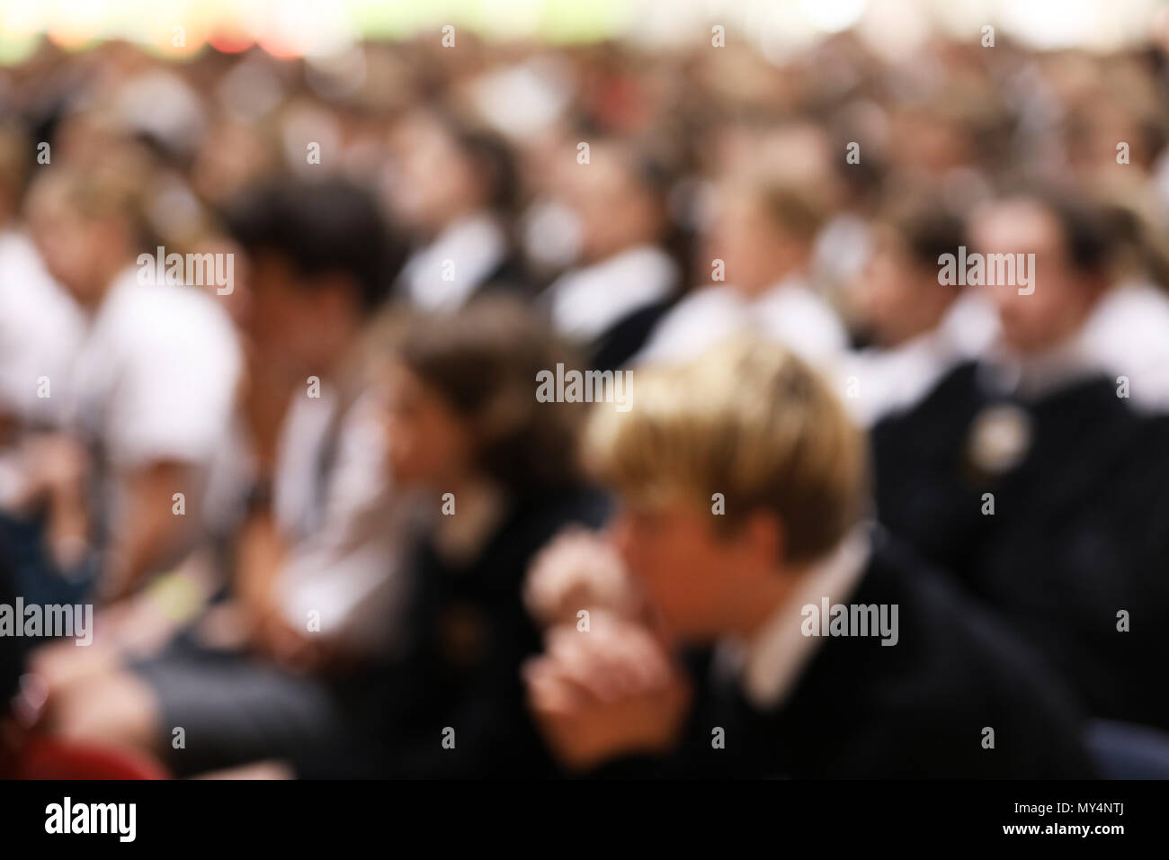 Gli studenti in uniforme seduto ascolto attento alla high school gruppo rivolto verso la stessa direzione. heavy sfumata per l'anonimato e effetto di sfondo Foto Stock