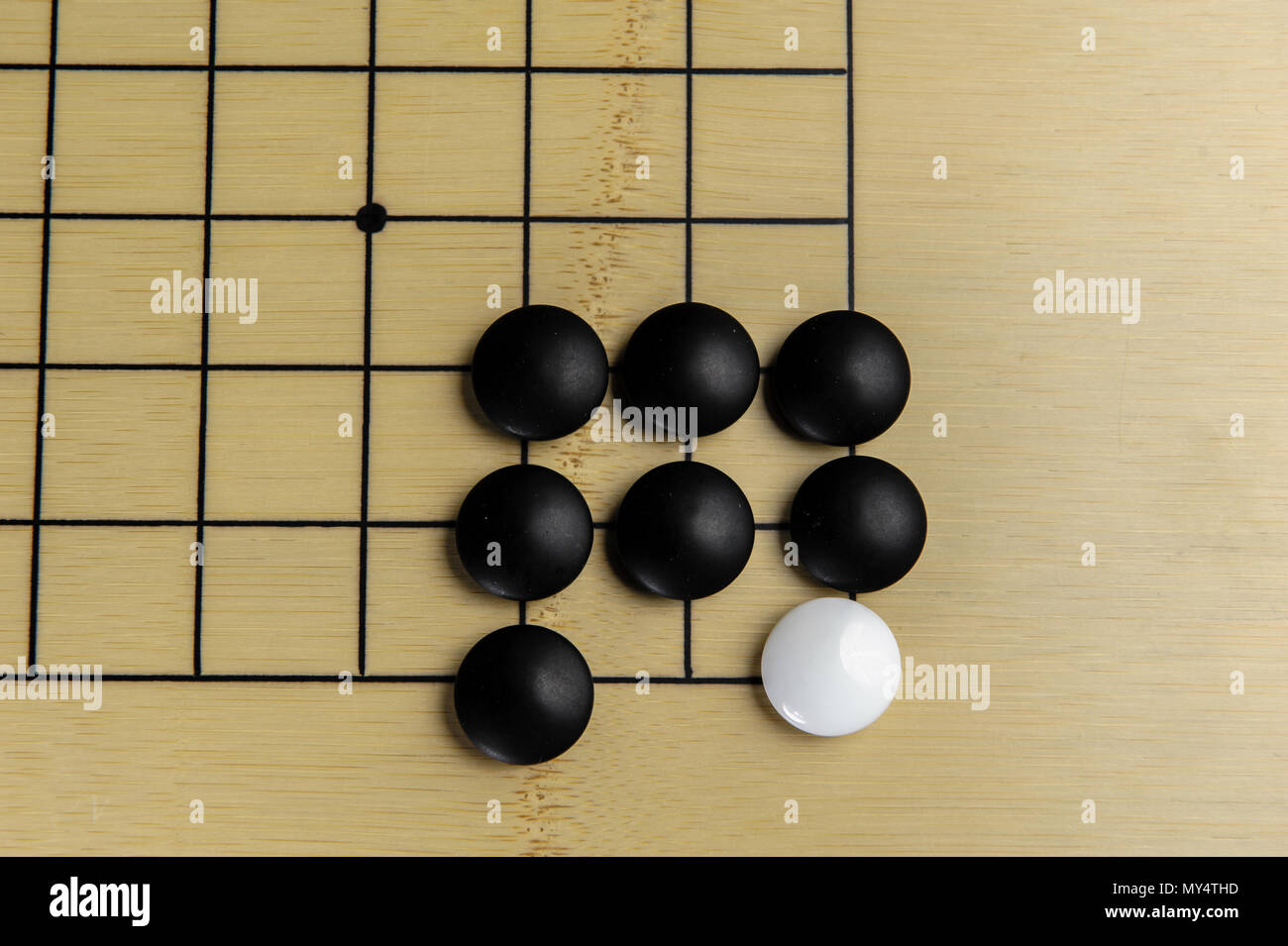 Giocando con il bianco e nero delle pietre sul bordo di bambù Foto Stock