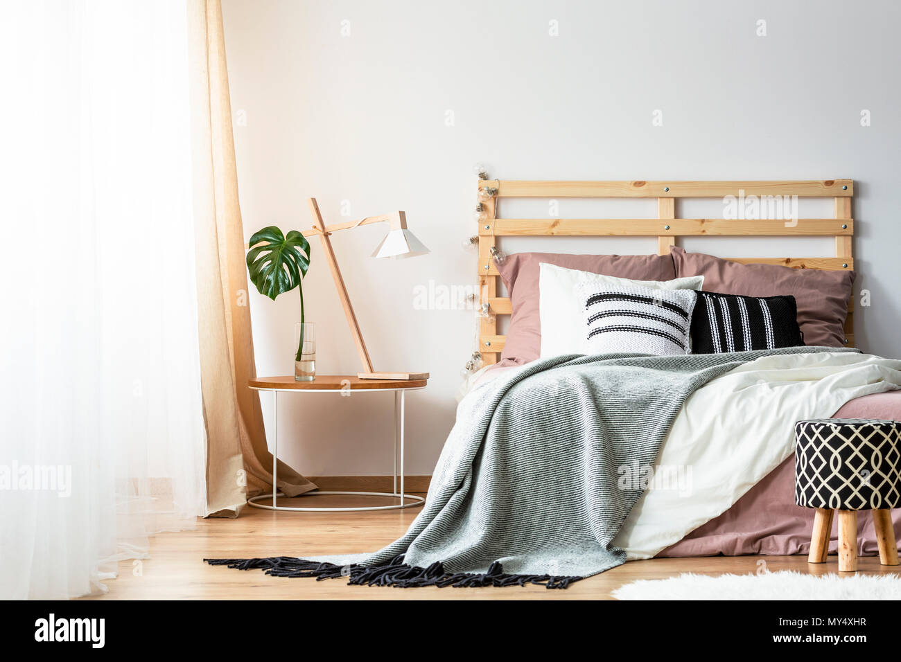Sgabello modellato accanto al letto con testiera del letto in legno nella camera  da letto interno con lampada sul tavolo. Foto reale Foto stock - Alamy