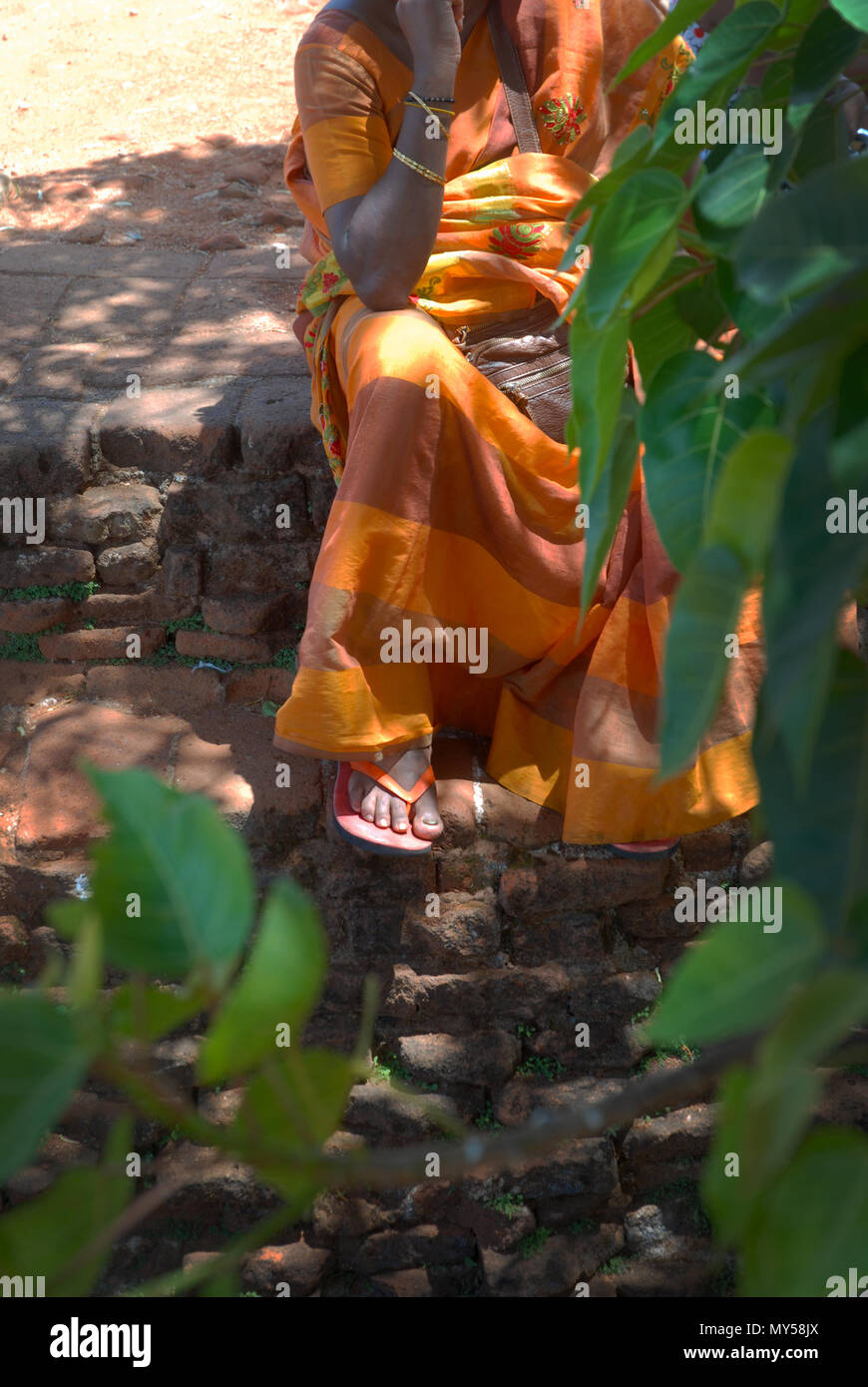 Donna seduta con saree arancioni, fortezza di Sigiriya Rock, Sigiriya, Provincia Centrale, Sri Lanka. Foto Stock