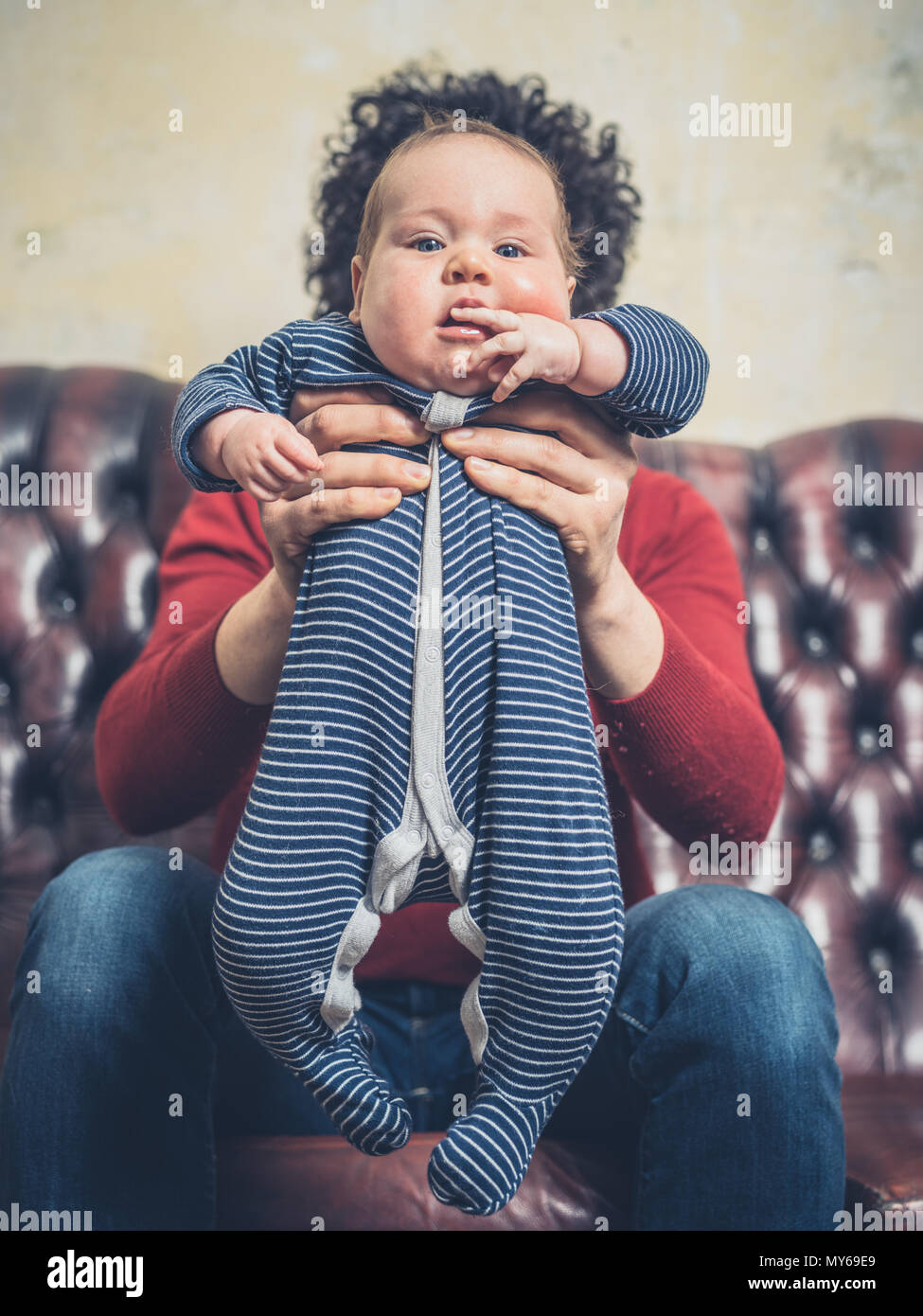 Un giovane padre è seduta su un divano con il suo piccolo bimbo Foto Stock