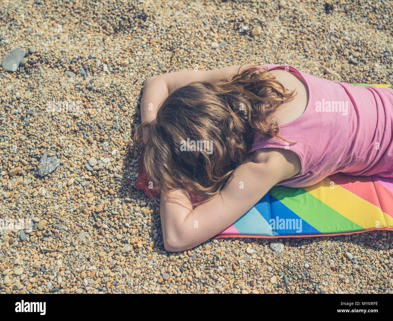 Una giovane donna dorme sulla spiaggia in estate Foto Stock