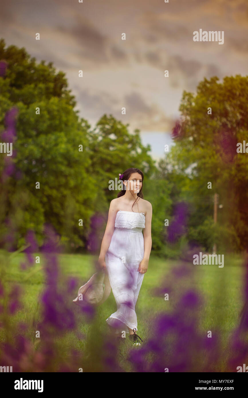 Giovane ragazza sul campo selvaggio con fiori d'estate Foto Stock