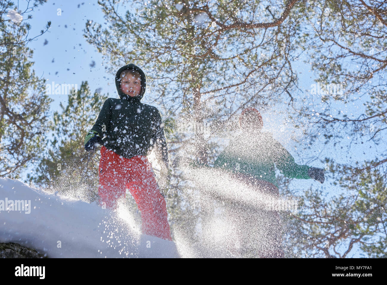 Due ragazzi saltando in snow, basso angolo di visione Foto Stock