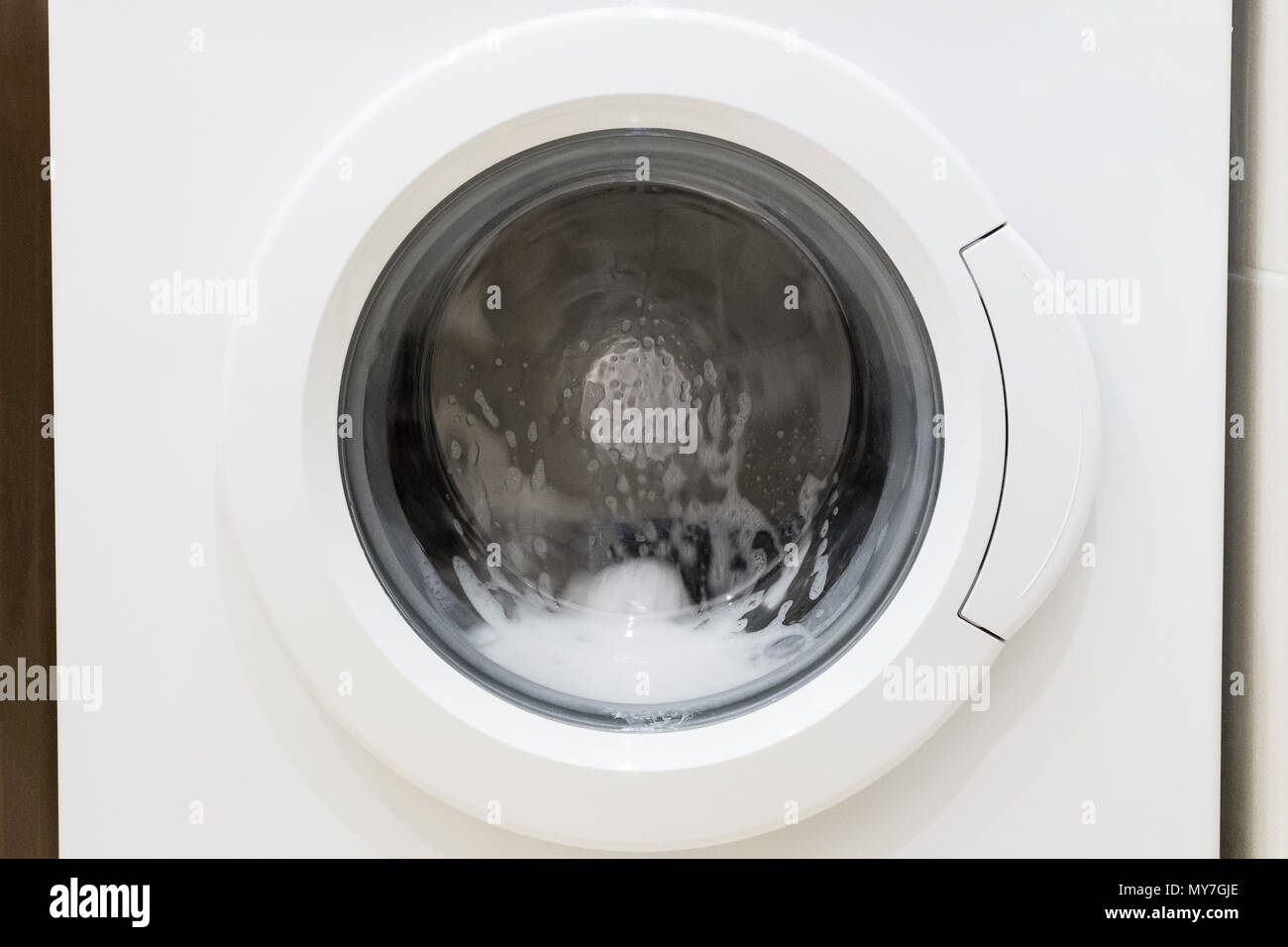 La porta della lavatrice con i panni rotanti all'interno. Tipo di schiuma  Foto stock - Alamy