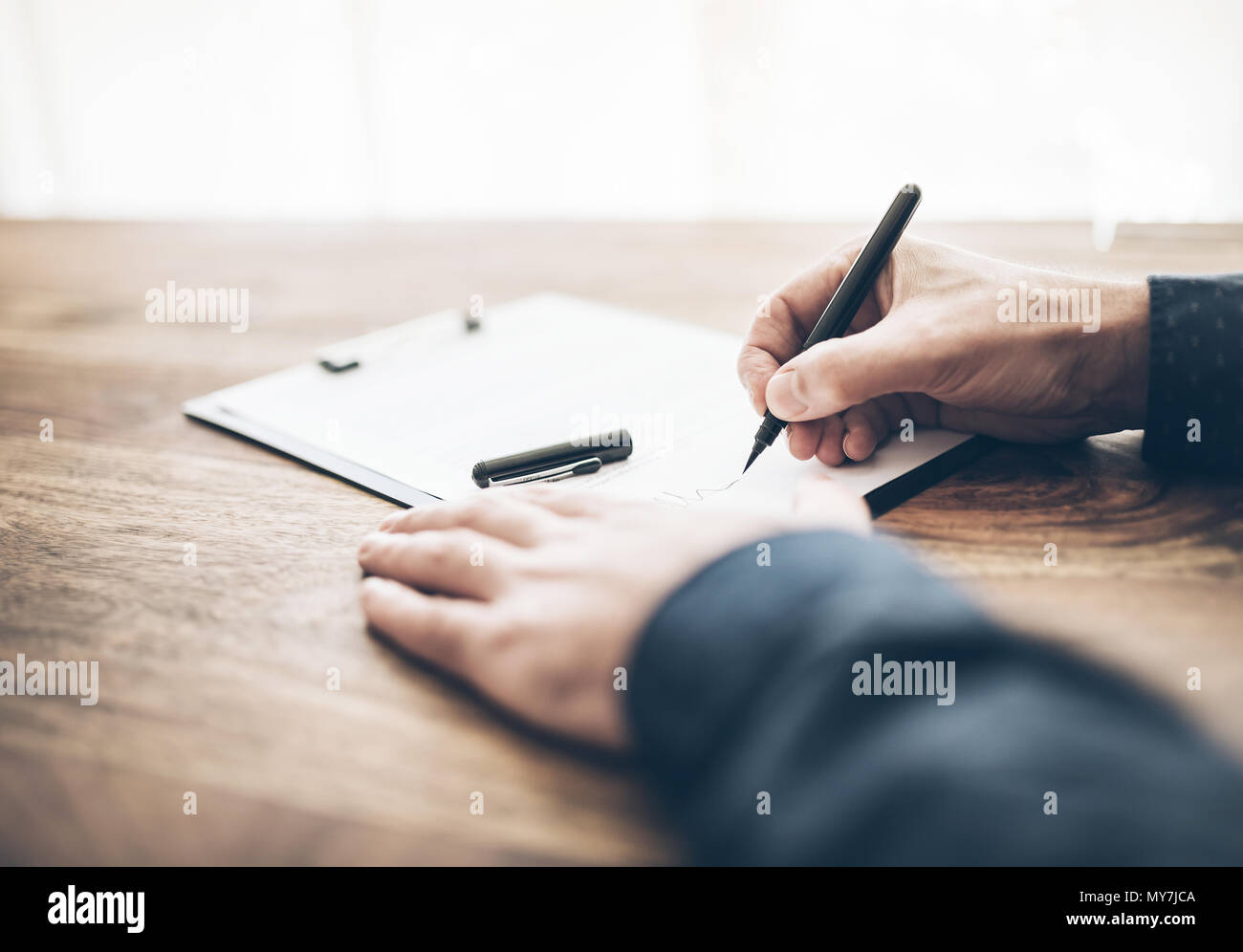 Close-up di imprenditore firma un contratto o documento sulla scrivania in legno Foto Stock