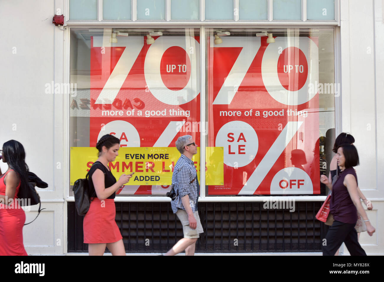 I turisti e gli amanti dello shopping a piedi passato negozi con il 70% di ulteriore riduzione e l'estate vendita segni, su Long Acre, Covent Garden Foto Stock