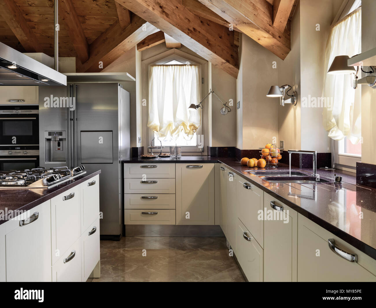 Moderna cucina interno nella camera mansardata con cucina a isola e soffitto in legno Foto Stock