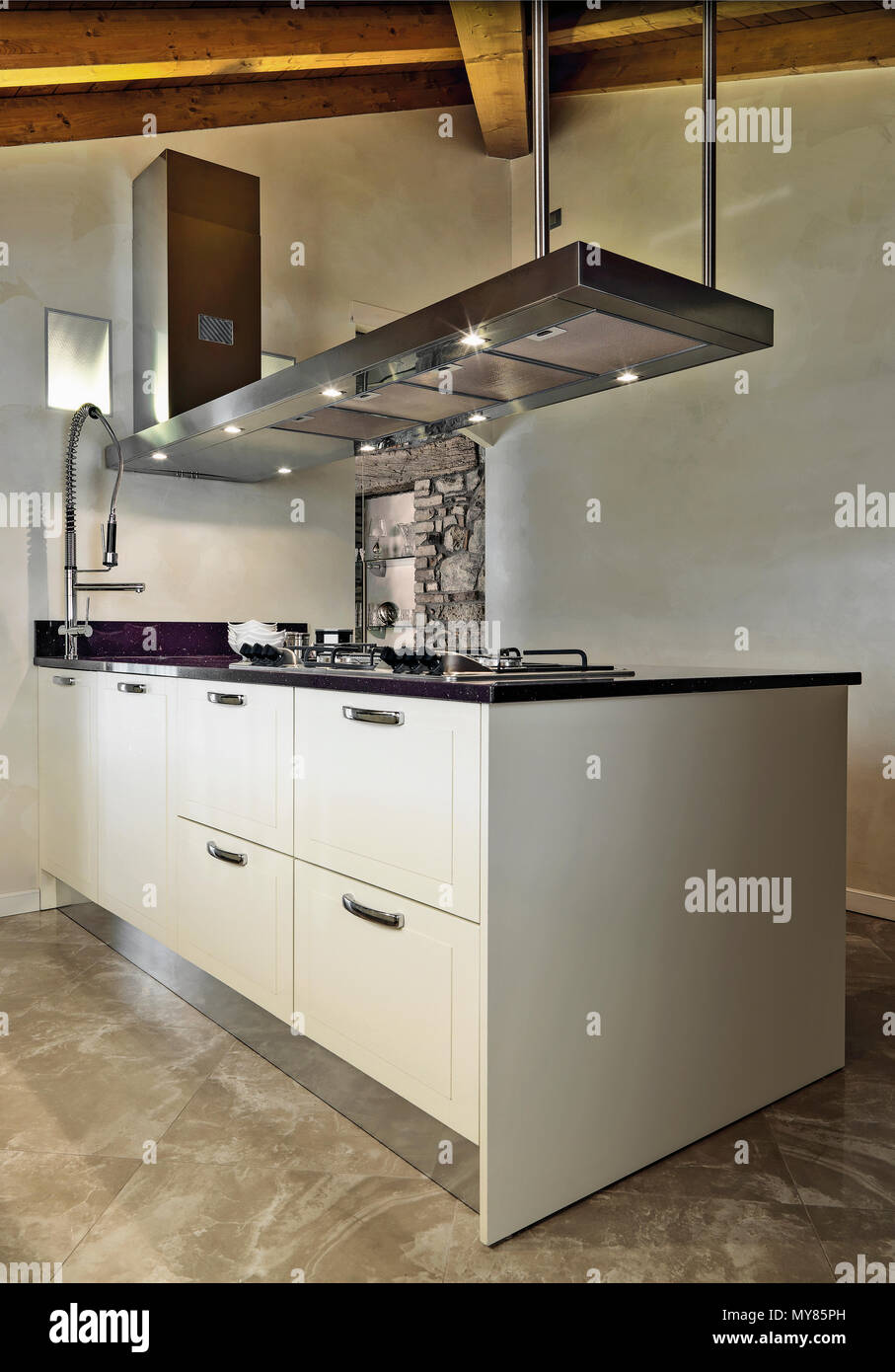 Moderna cucina interno nella camera mansardata in primo piano l'Isola per cucina con pavimento in marmo e soffitto in legno Foto Stock