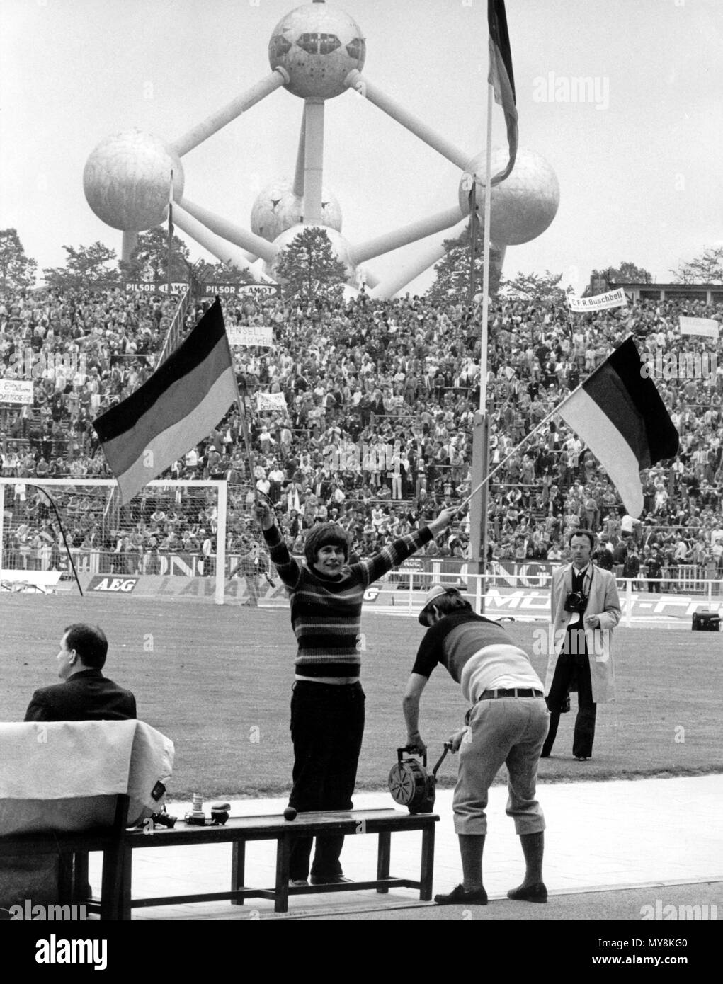Una ventola femmina sventolano due bandiere tedesco del 18 giugno 1972 nell'Heysel Stadium di Bruxelles, Belgio, prima della finale del campionato europeo di calcio. La squadra nazionale di calcio tedesca ha vinto la finale contro l'URSS 3-0 davanti a 50.000 spettatori. L'Atomium landmark può essere visto svettare sopra lo stadio in background. | Utilizzo di tutto il mondo Foto Stock