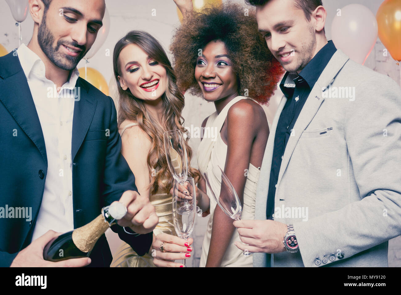 Uomo di apertura della bottiglia di champagne sulla celebrazione nel club Foto Stock