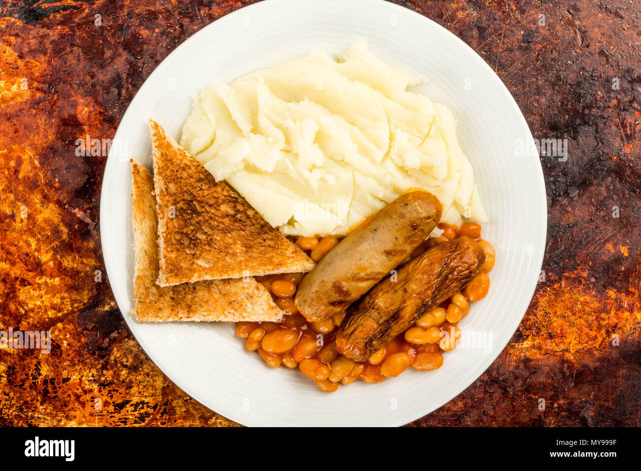 Salsicce di maiale con fagioli e purè di patate e pane tostato Foto Stock