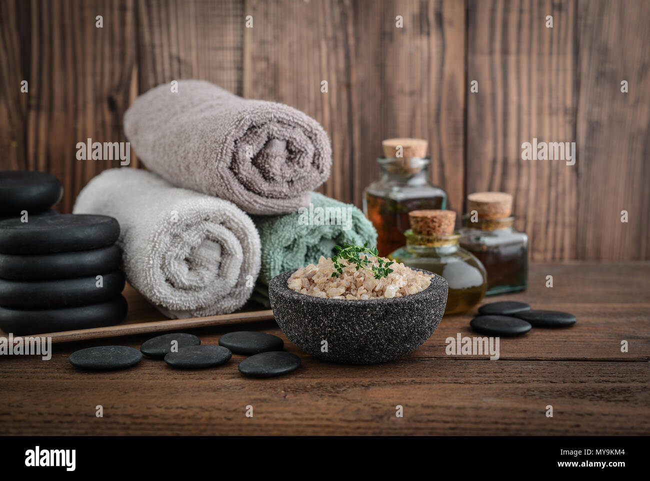 Asciugamani con sale marino, massaggio olio in bottiglia vintage, candele e  pietre per massaggio stone su sfondo di legno Foto stock - Alamy