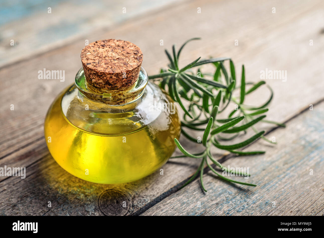 Olio essenziale di rosmarino in una bottiglia di vetro con tappo di sughero e di rosmarino fresco herb su sfondo di legno Foto Stock