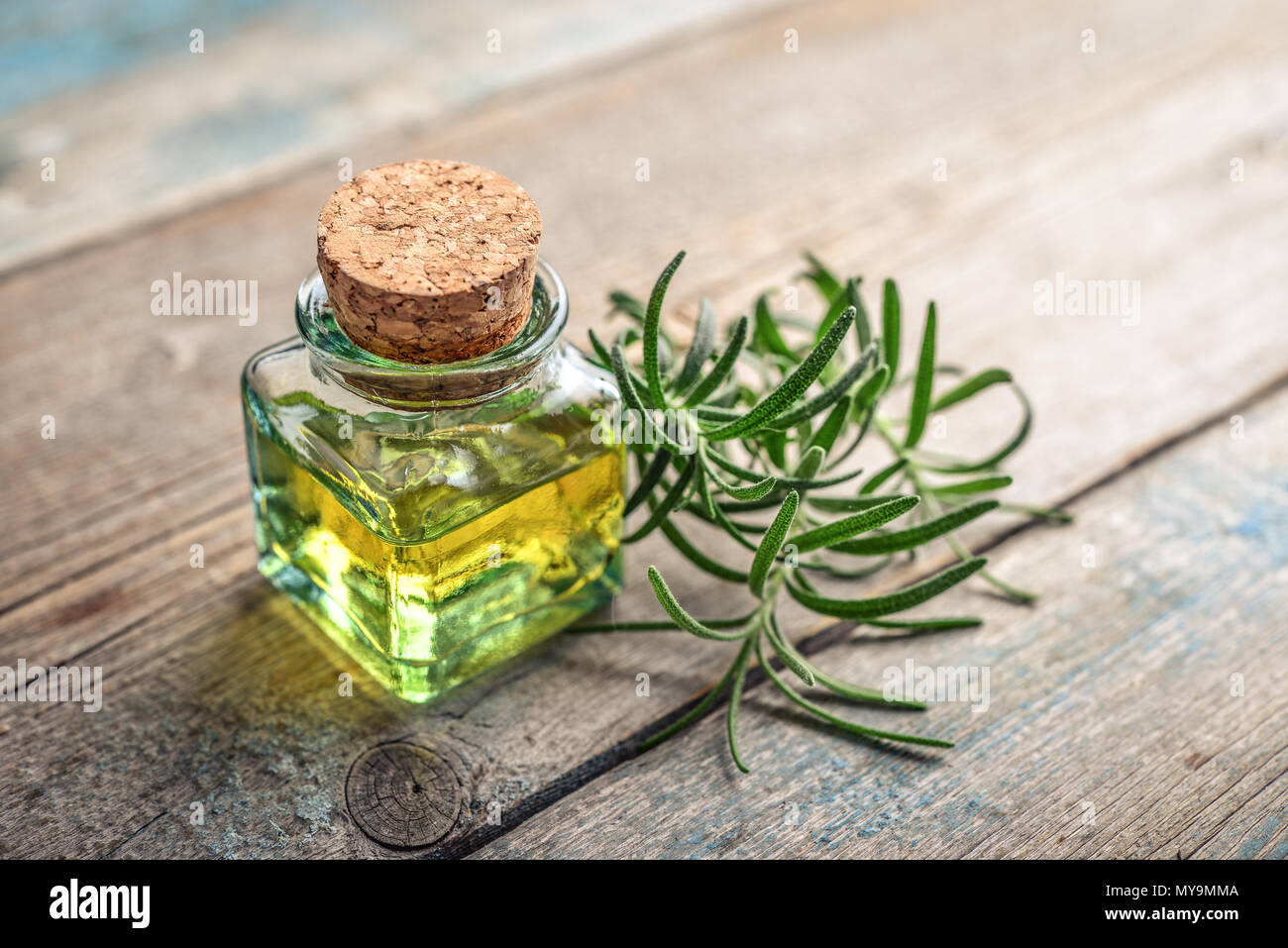 Olio essenziale di rosmarino in una bottiglia di vetro con tappo di sughero e di rosmarino fresco herb su sfondo di legno Foto Stock