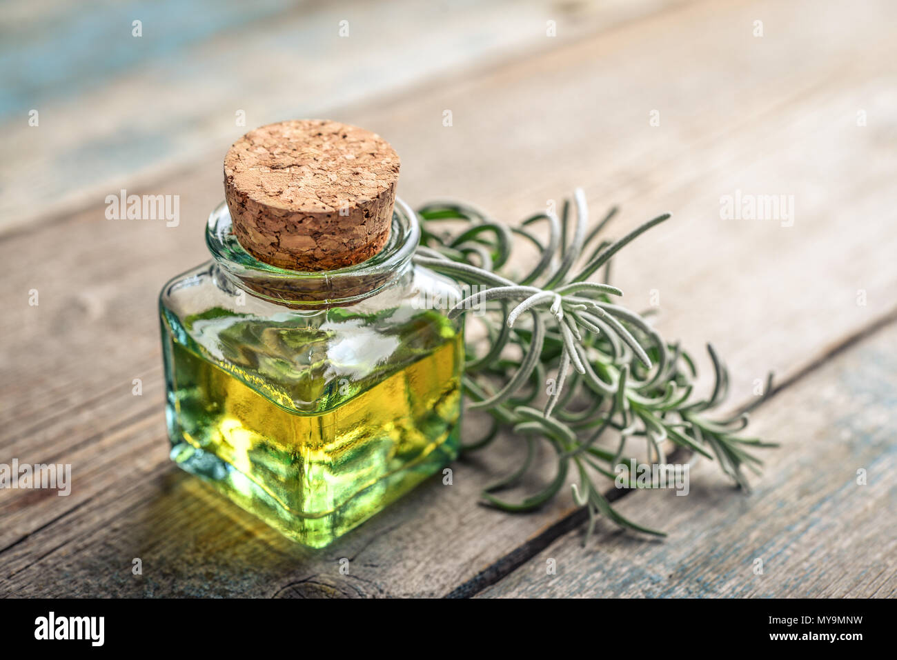 L'olio essenziale di lavanda in una bottiglia di vetro con tappo di sughero e fresche erbe lavanda su sfondo di legno Foto Stock