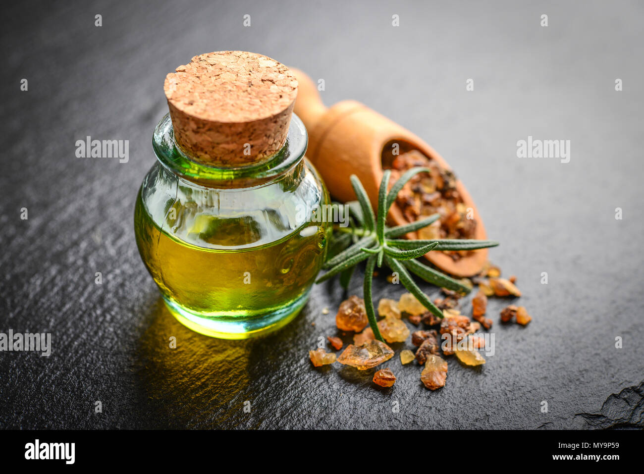 Una bottiglia di mirra olio essenziale di mirra resina su un nero ardesia sfondo Foto Stock