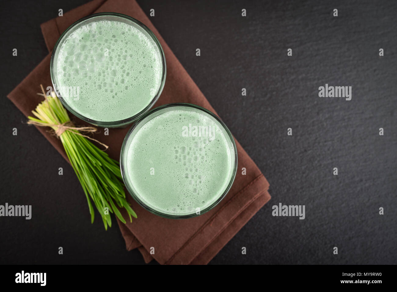 Due verde erba d'orzo scatti con lame di giovani orzo su uno sfondo nero, vista dall'alto Foto Stock