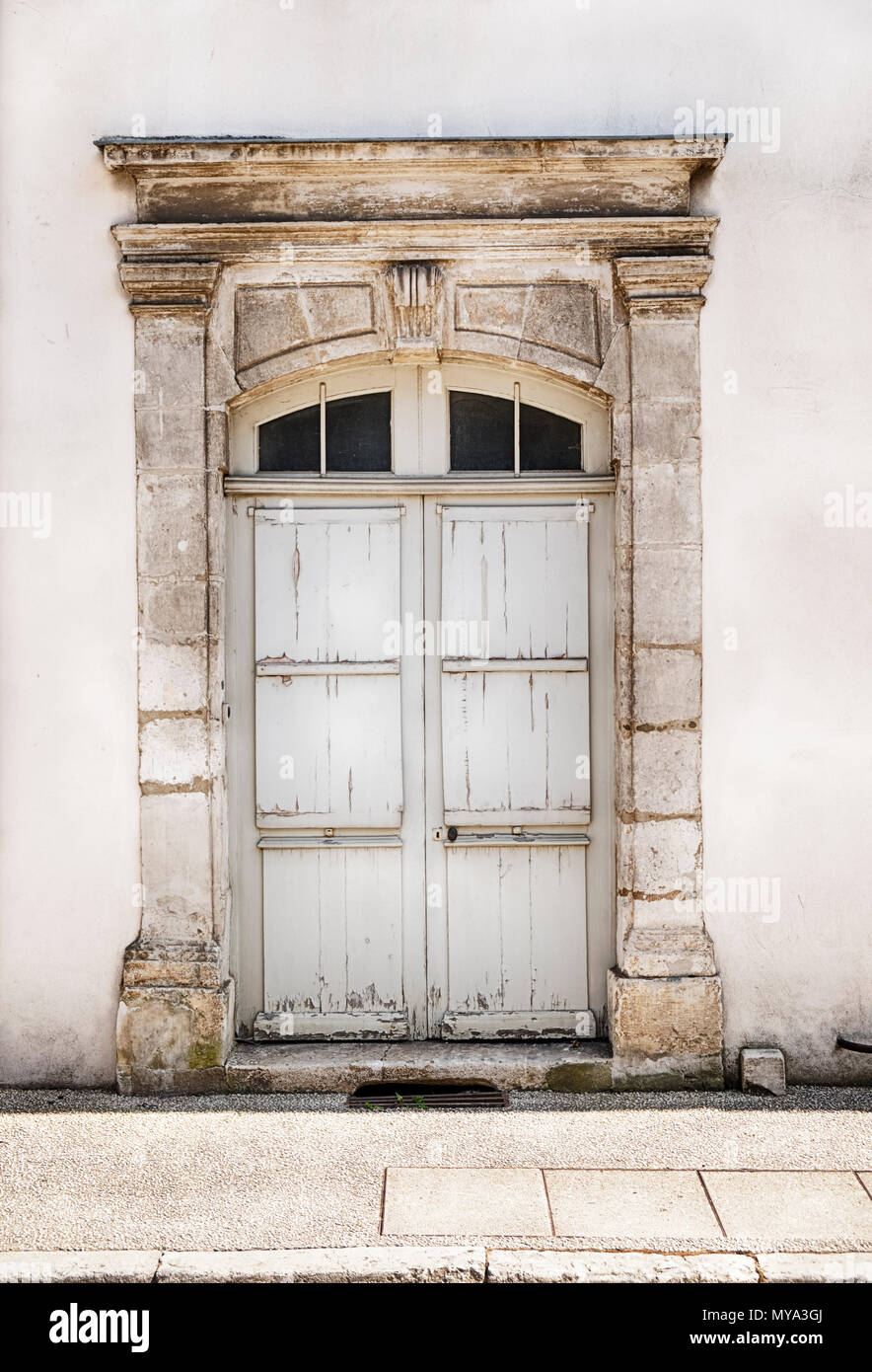 Una vecchia porta di legno con una classica cornice in pietra ancore di una voce in un altrimenti senza caratteristiche di rilievo casa di Chablis regione della Francia. Foto Stock