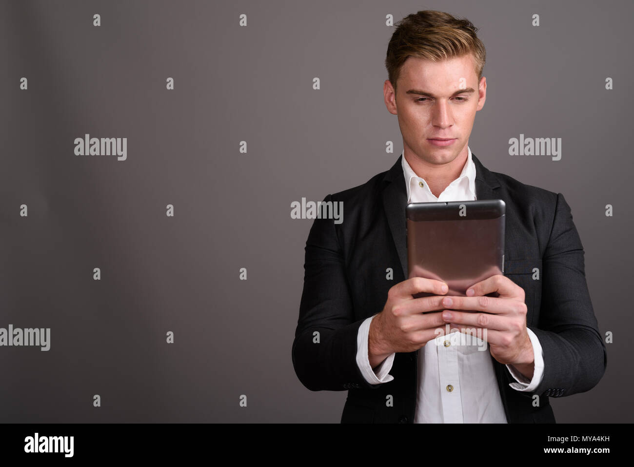 Bel giovane imprenditore con capelli biondi indossare tuta contro Foto Stock