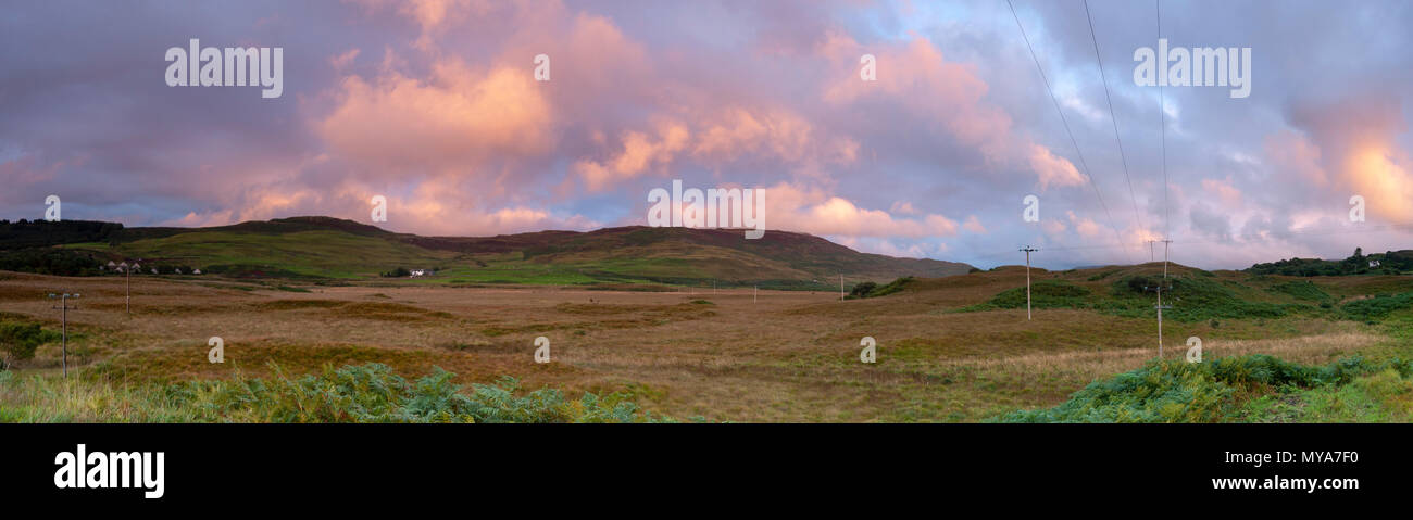 Cucito panorma di una vista generale di colline con ora d'oro tramonto luce della sera sotto illuminazione Nuvole rosa sulla Isle of Mull, Highlands, Scozia, Foto Stock