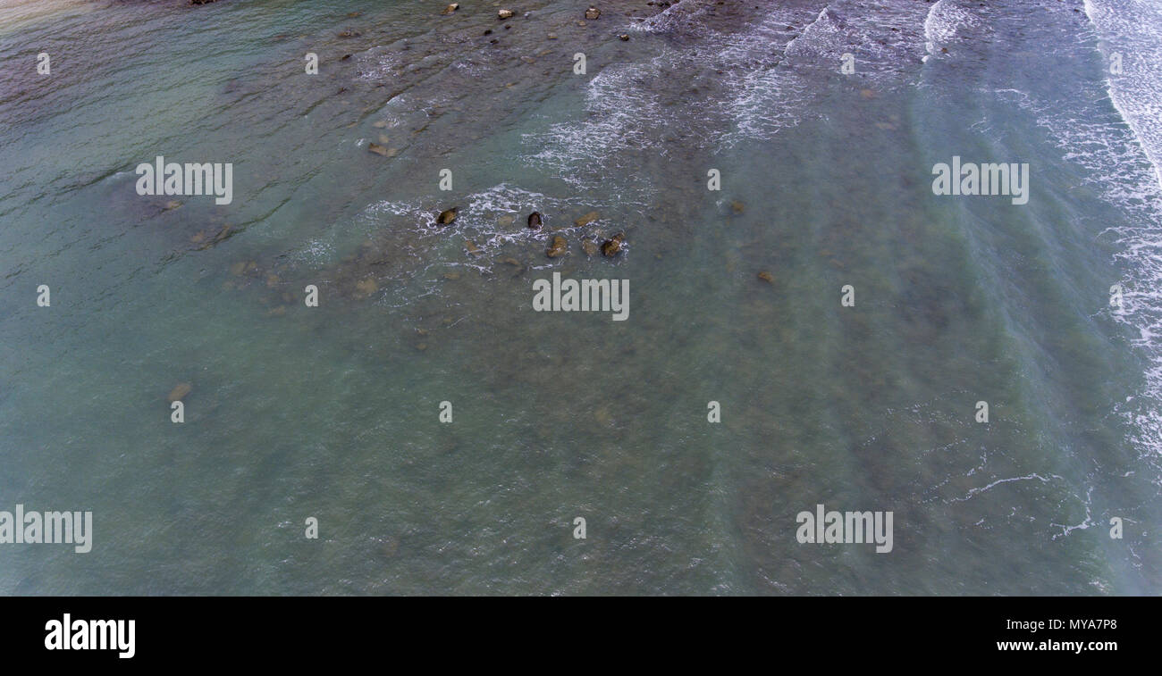 Le piccole onde che si infrangono sulla spiaggia attrezzata di sabbia e scogli a Koh Chang, Thailandia. Foto Stock