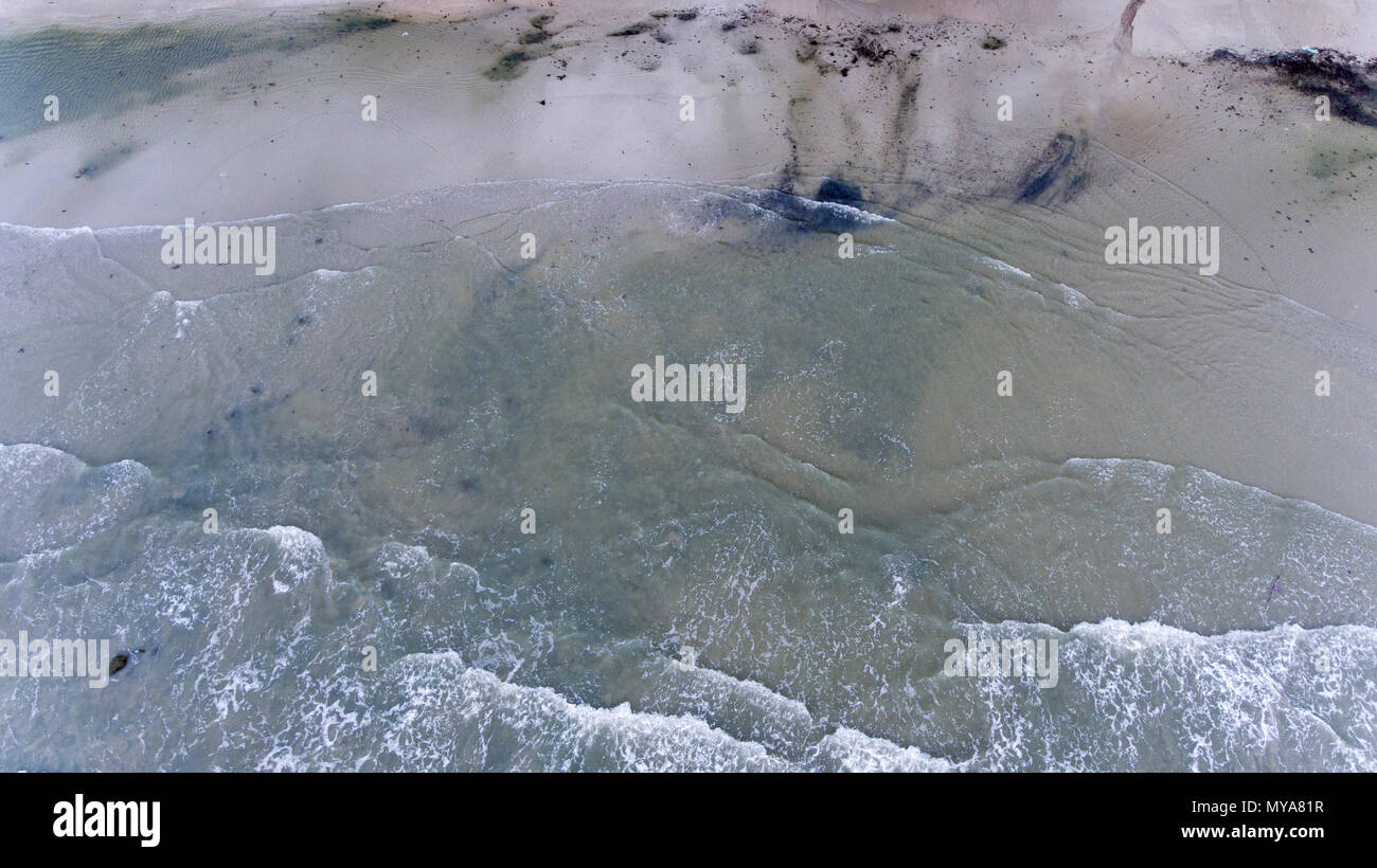 Le piccole onde che si infrangono sulla spiaggia attrezzata di sabbia e scogli a Koh Chang, Thailandia. Foto Stock