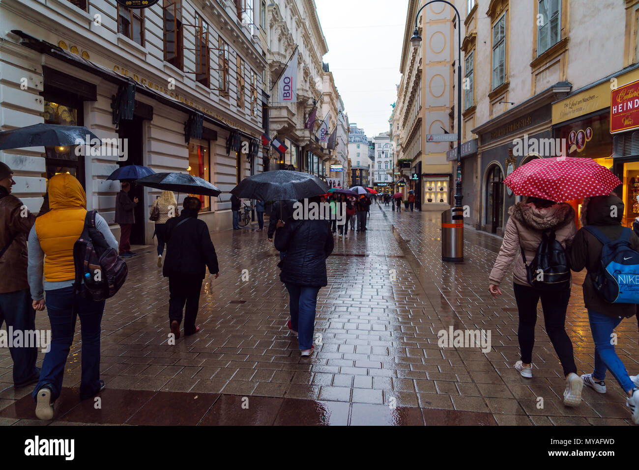 Vienna, Austria - 22 Ottobre 2017: turisti sotto ombrelloni colorati per le strade della città vecchia in un giorno di pioggia Foto Stock