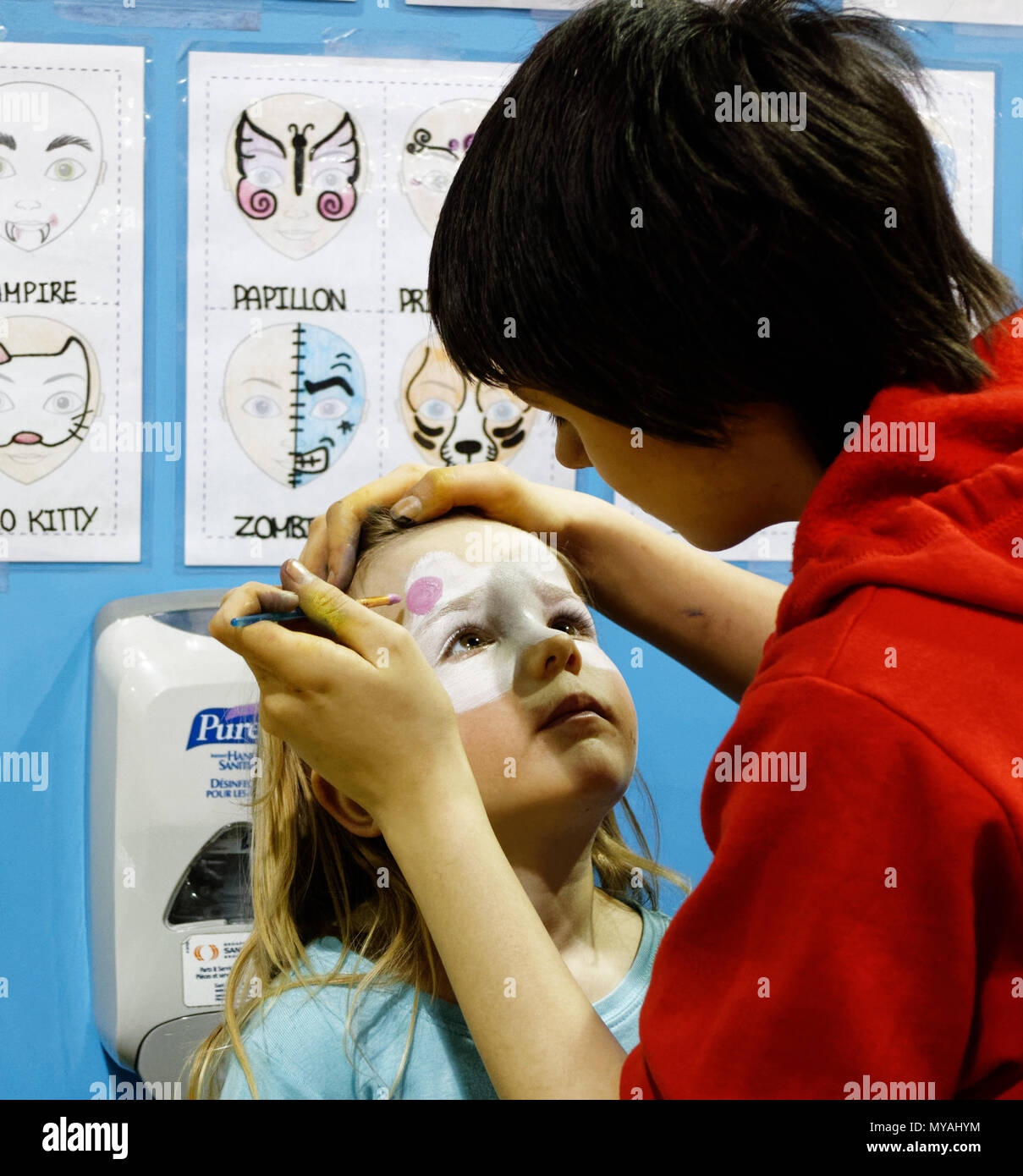 Una donna face painting una bambina (3 anni) come Hello Kitty ad una festa per i bambini Foto Stock