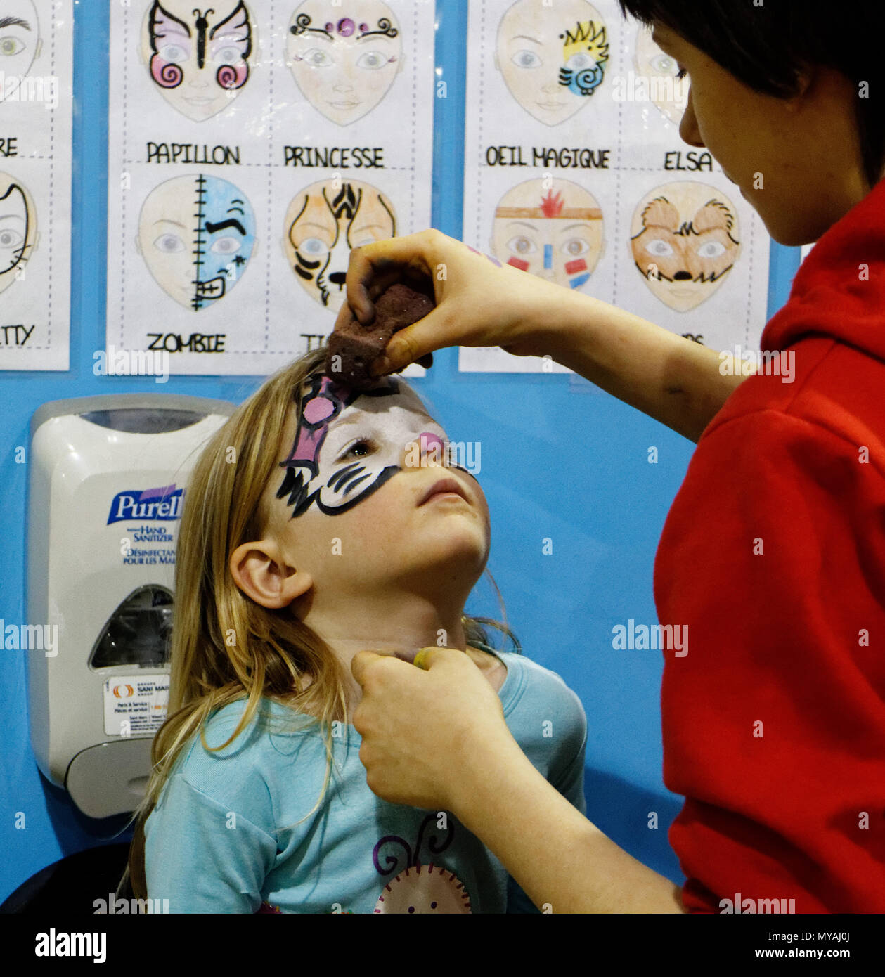 Una donna face painting una bambina (3 anni) come Hello Kitty ad una festa per i bambini Foto Stock