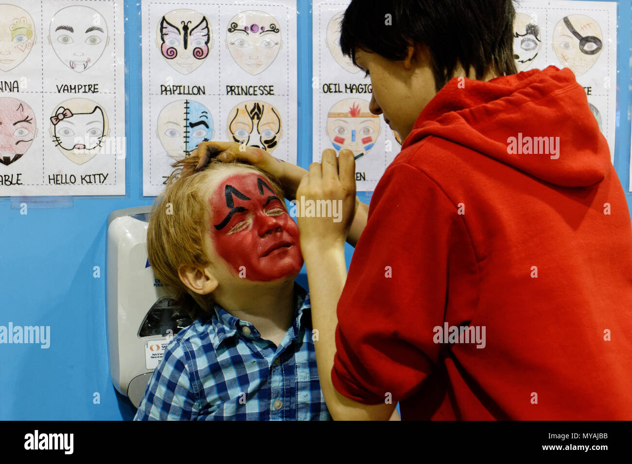 Un po' ragazzo (4 anni) avente il suo volto dipinto di rosso brillante Foto Stock