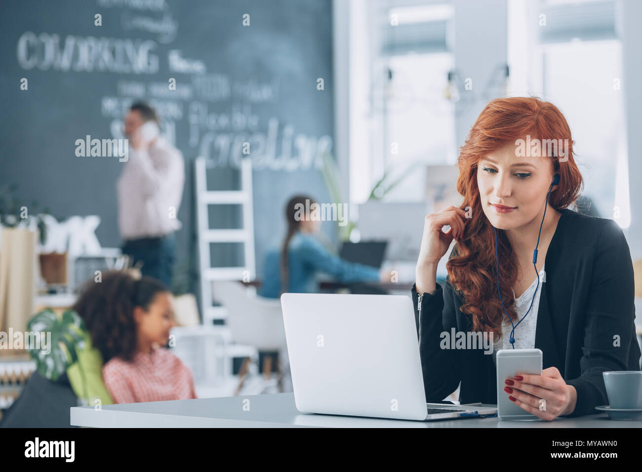 Rilassata, giovane lavoratore di agenzia creativa utilizzando laptop, ascolto di musica Foto Stock