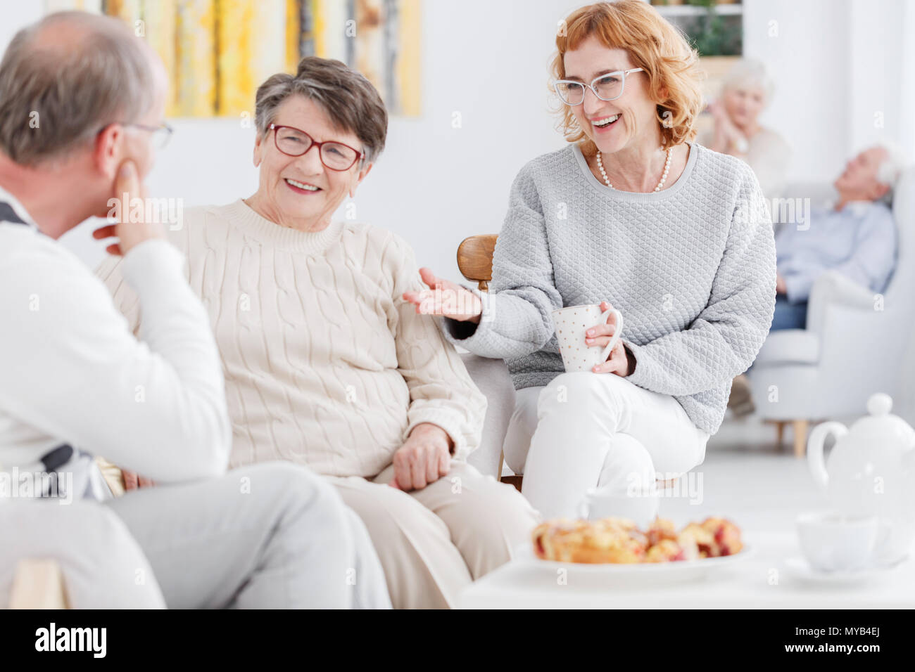 Senior felici donne e uomini anziani spettegolare ad un tea party Foto Stock
