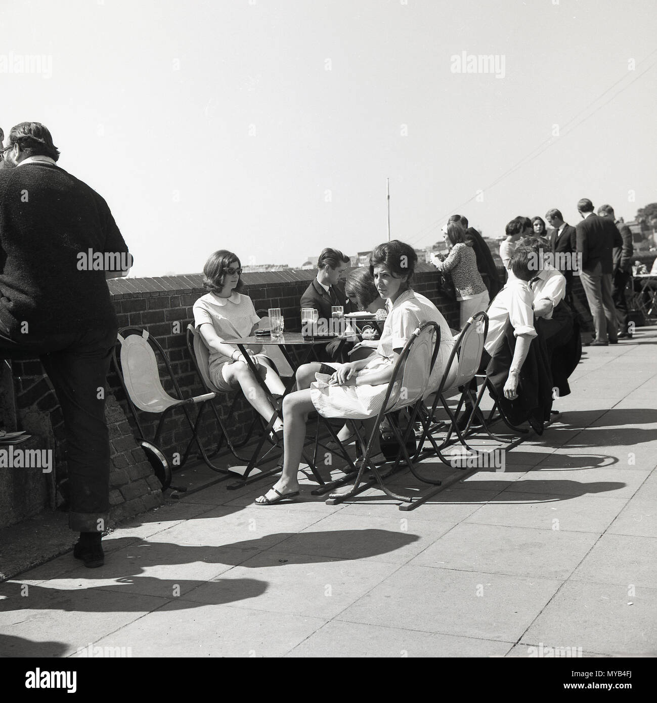 Anni sessanta, storico, le persone aventi un drink durante la pausa pranzo, waterside dal fiume Tamigi, al di fuori della colomba pub, superiore posta, Hammersmith, London, Regno Unito. Foto Stock